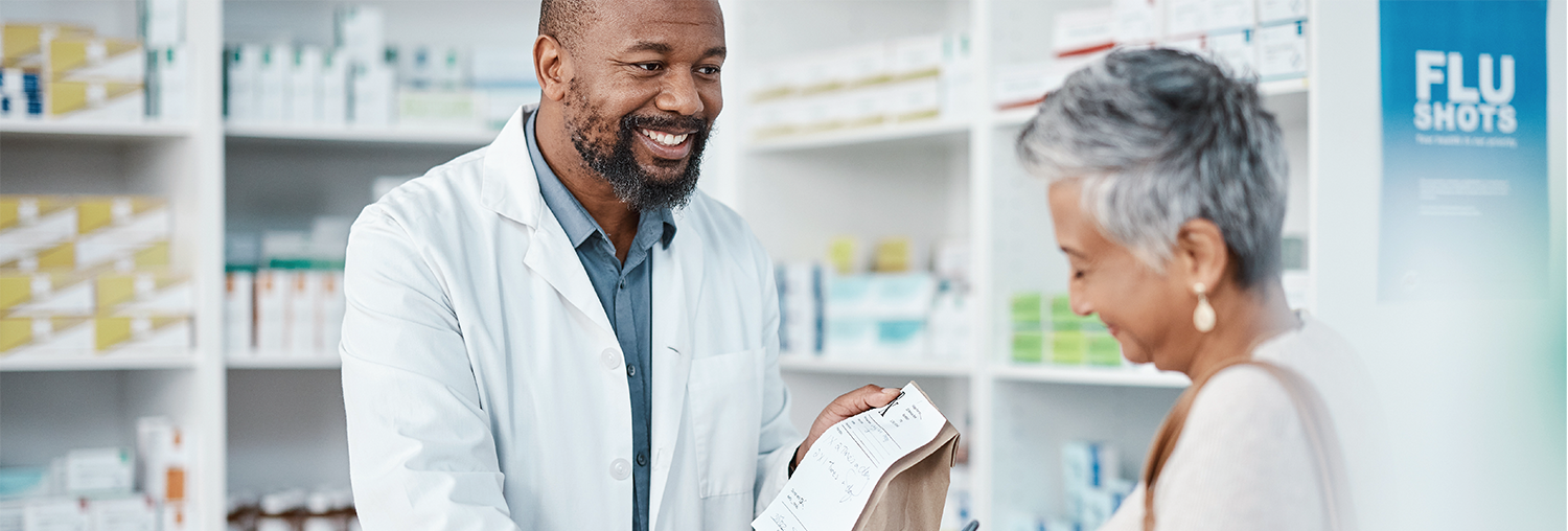 young pharmacist hands mature woman her prescription with a smile